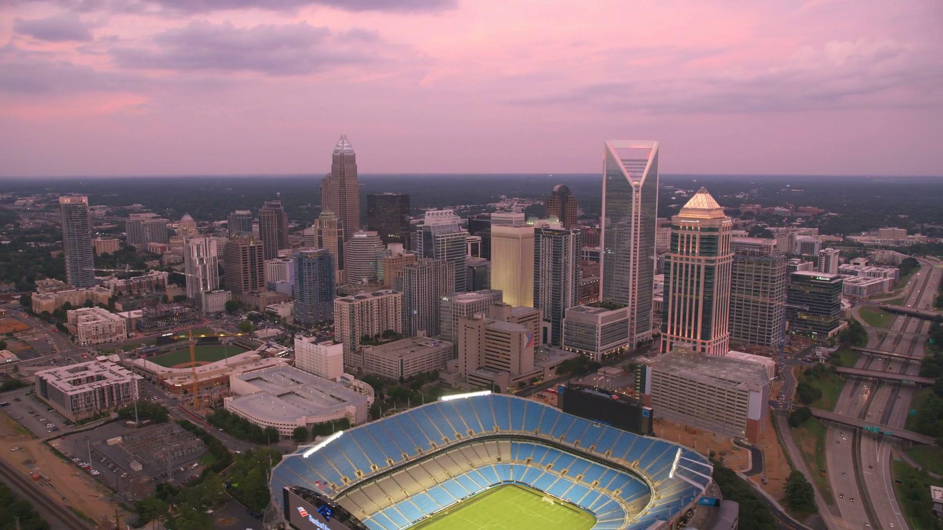 Aerial view of the Uptown Charlotte skyline and Bank of America Stadium at sunset